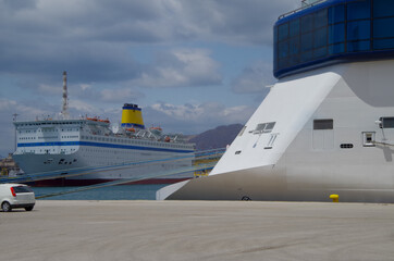 Passenger ferry and stern of modern Celebrity cruiseship or cruise ship liner with duck tail in...