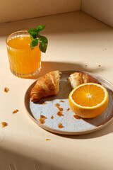 food and eating concept - glass of orange juice with peppermint and croissant on plate for breakfast
