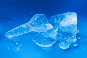 Broken bottle of clean, transparent, natural ice on a blue background. Purity and freshness concept, ice drink