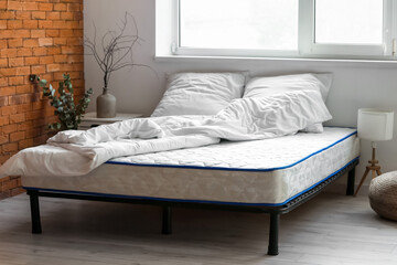 Bed with comfortable orthopedic mattress in room