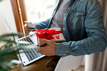 Man using laptop computer and credit card, ordering gifts for Valentines day, Womans Day, Christmas. Shopping online