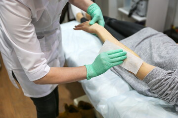waxing procedure in the beautician's office. woman's hand epilation with wax strip