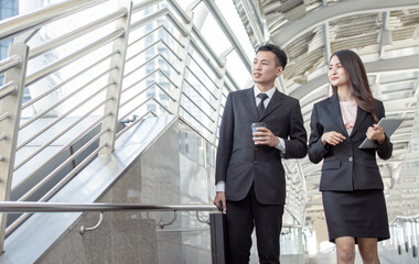 Two business man and woman talking and walking outside