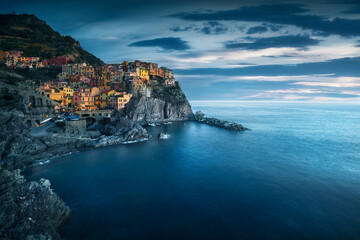 Manarola village, rocks and sea in blue hour. Cinque Terre, Italy.