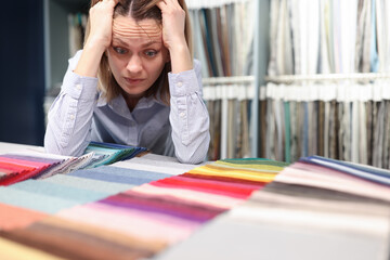 Confused woman chooses fabrics in t store