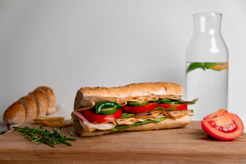 Fresh submarine sandwich with ham, cheese, tomato, cucumber, lettuce and onion isolated on white background.