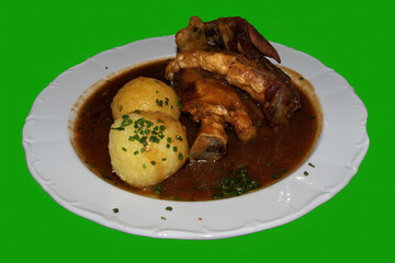 A typical Bavarian meal. In Bavaria, this is called Schweinshaxe. This refers to a grilled portion of a pork leg served with potato dumplings.  Isolated with green background.