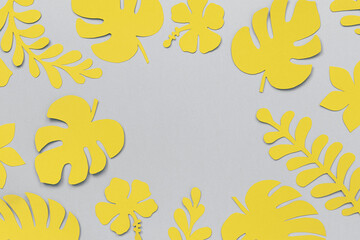 Yellow tropical leaves from paper with copy space for your design or lettering text on grey background. Flat lay, top-down composition, creative paper art. Trendy colors 2021