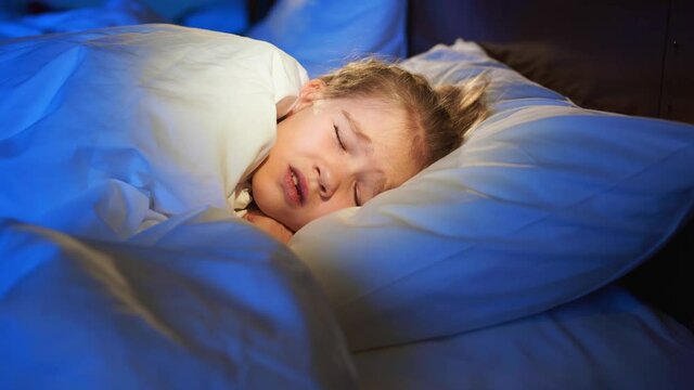 A little girl naps in bed, sees a nightmare, cry and wake up