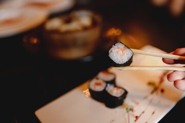 Copy space close-up traditional Japanese hossomaki  sushi roll salmon placed between chopsticks. Healthy food concept.