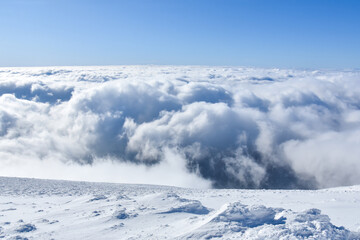 Fototapeta na wymiar Winter mountain. Snowy peak high above the clouds. Show and clouds on Dry Mountain, Serbia