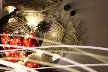 wicker basket with red Christmas balls, knitted scarf and mittens, garland lights. atmosphere of winter holidays