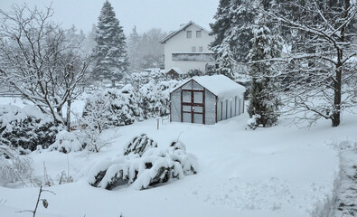 Fototapeta na wymiar Gewächshaus im Garten mit viel Schnee eingeschneit Wintergarten Winter