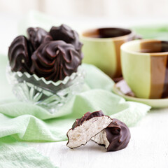 White marshmallow in chocolate and a mint leafon a wooden table. the still life, selective focus.