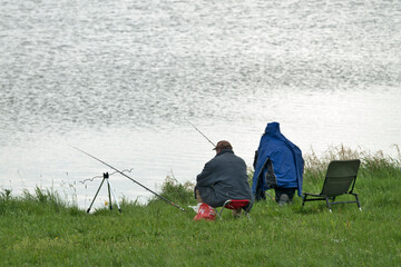 Two people are fishing on the lake shore