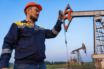 Oil refining. A man takes a sample of oil at an oil field