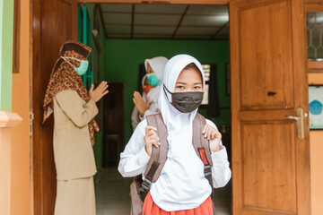 portrait of students saying goodbye to teachers with social distancing protocols in the school