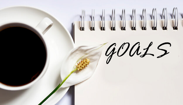 Time GOALS , planning concept. notebook with text on white background with coffee
