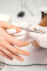Manicure master is removing cuticles with a nail clipper in a nail salon