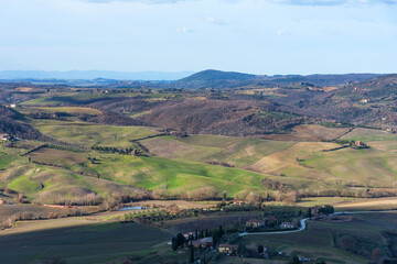 Picturesque winter landscape view of Tuscany with stone houses, colorful hills, fields and vineyards in Italy.