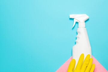 Yellow gloves, microfiber cloth and spray cleaner on a blue background, top view, copy space. Cleaning supplies.