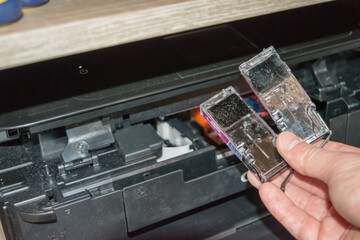 Replacing the ink in the printer, the human hand takes out the cartridge