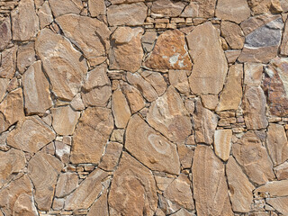 A decorative exterior wall with rough stonework lined in a chaotic manner. Background texture