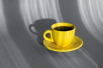 Yellow cup of coffee on a gray background. Demonstration of gray and yellow colors trendy colors 2021