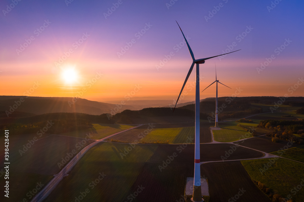 Wall mural Aerial view of colorful autumn sunset beyond wind turbines