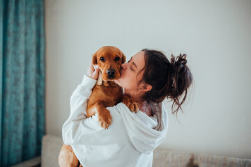A girl in a white hoodie kisses a dog