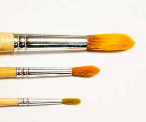 Set of three art brushes made of natural bristles of different sizes isolated on white background.