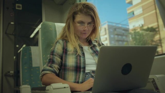 Young woman on commuter train to city or airport express work remotely on laptop, send emails, reply to texts from laptop connected to internet hotspot.Millennial freelancer commute and stay connected