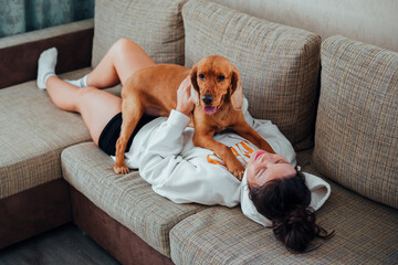 Woman playing with dog on sofa lying down