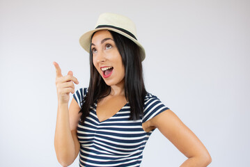 Naklejka premium Portrait of a happy young woman dressed in casual t-shirt pointing fingers up at copy space isolated over white background