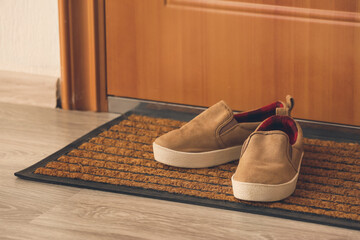 Little boy shoes near door on mat
