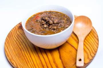 Bowl of lentils on a wooden tray and white background