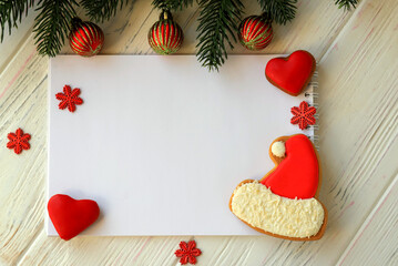 White notebook for Christmas wishes, goals, tasks, recipes for the New Year 2021 among tree, gingerbread cookies in form of Santa Claus hat, hearts. Christmas decorations on wooden background