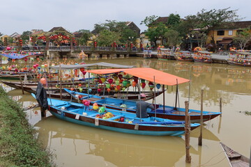 Fototapeta na wymiar Hoi An, Vietnam, December 10, 2020: Boats adorned with multi-colored lanterns on the bank of the Thu Bon River in Hoi An