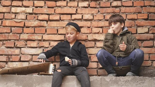 Two poor street boys need help asking help food donation from strangers, on street at big city, begging. Shelter concept.