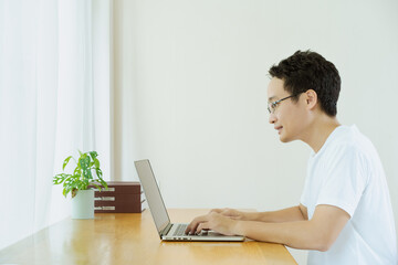 Happy Asian young businessman in relax casual style having a video conference with his colleague