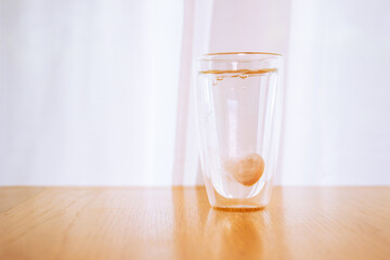 Tablet of calcium effervescent melting in a drinking water close up with copyspace. 