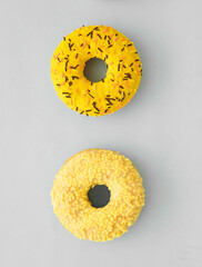 Delicious donut in yellow color on gray background.