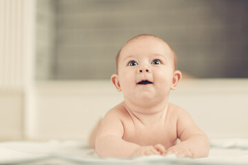 pretty baby lying down and looking up in surprise