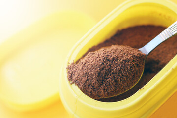 Cocoa spoon and yellow jar, orange background