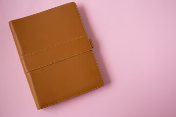 Top view of brown leather notebook isolated on pink