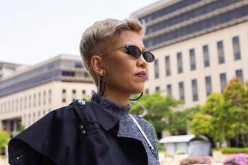 A Young Asian woman with a white dark black sunglasses on the street in Kuala Lumpur, Malaysia. A young model with blond hair and fashionable designer clothes in downtown Kuala Lumpur	