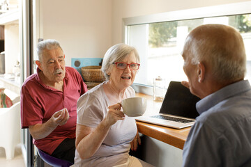 gruppo di anziani fa colazione al bancone chiacchierando amabilmente . Sopra il bancone in legno un...