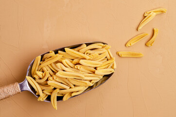 Yellow dry pasta in a metal scoop
