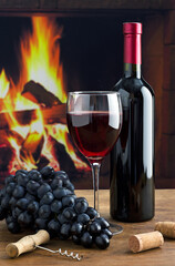Wine bottle and wineglass on the background of the fireplace.