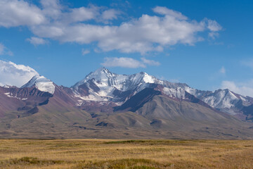 View of snow-capped Trans-Alai or Trans-Alay mountain range in Sary Tash valley, Kyrgyzstan with pasture foreground along the Pamir Highway
